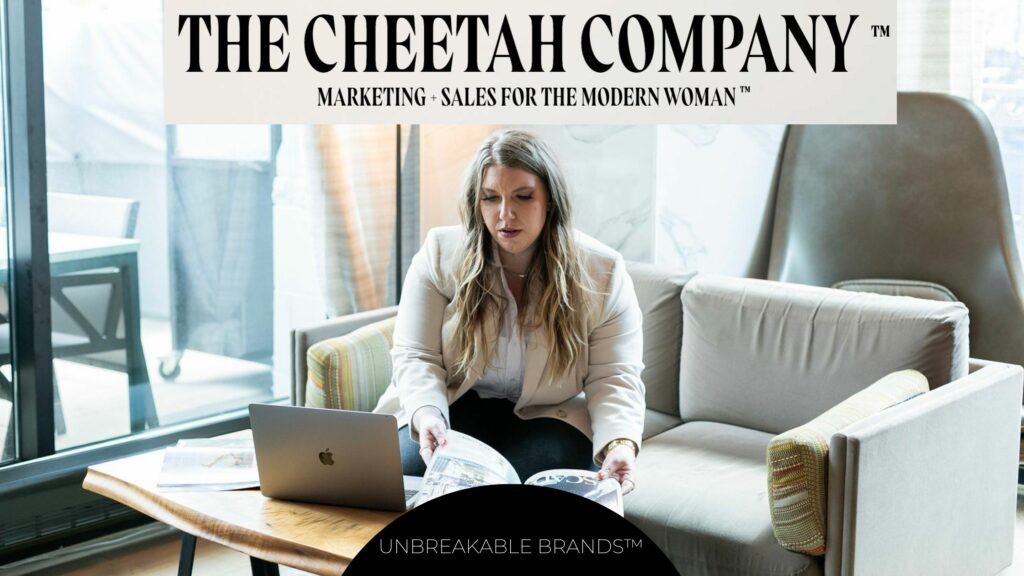 A girl sits on a couch next to a macbook while looking at a book. Text above her says, "The Cheetah Company™. Marketing + Sales for the Modern Woman™."